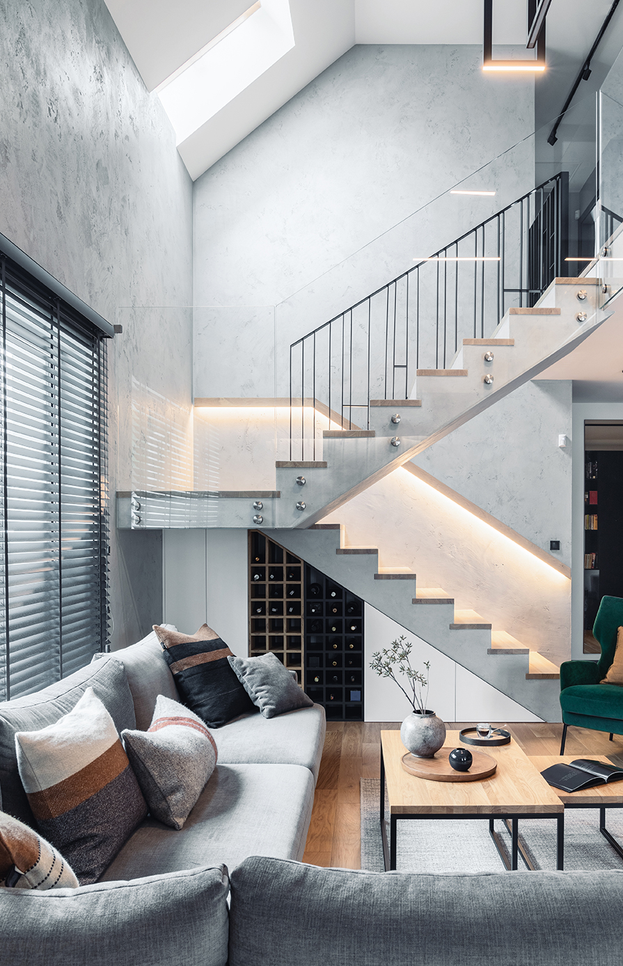 A wide shot of a modern staircase mid landing overlooking a living room.
