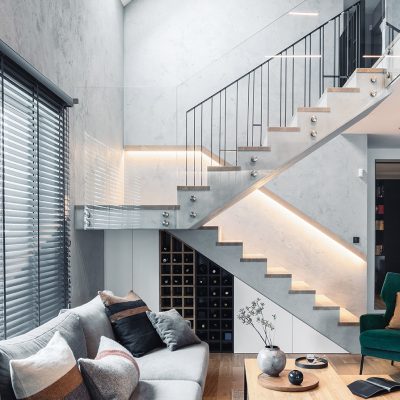 A wide shot of a modern staircase mid landing overlooking a living room.